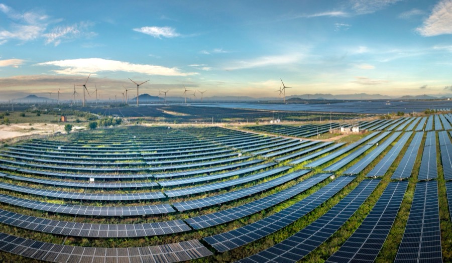 Usina solar fotovoltaica com aerogeradores ao fundo ao amanhecer